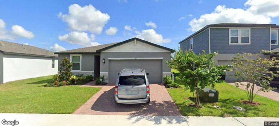 A grey car is parked in front of a grey garage.