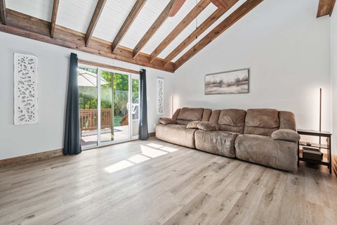 A living room with a large sectional sofa and a wooden floor.