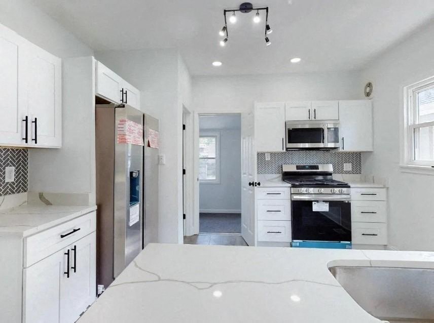 a white kitchen with a sink and a refrigerator