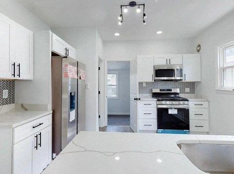 a white kitchen with a sink and a refrigerator