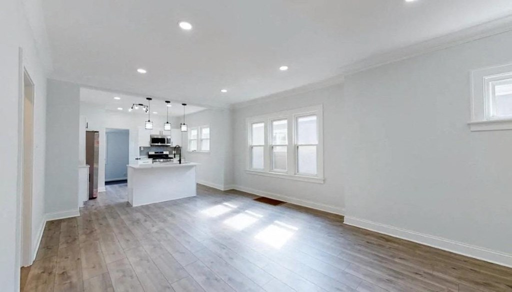 an empty kitchen and living room with white walls and wood floors