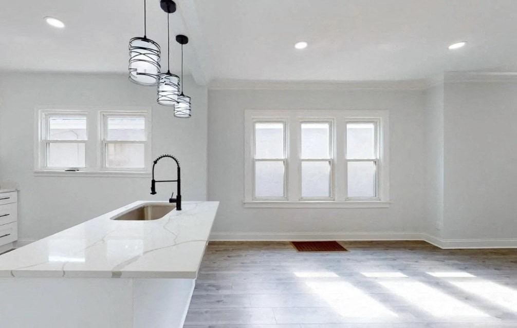 an empty kitchen with white cabinets and a sink and windows