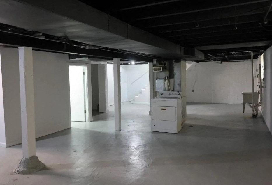 an empty basement with a refrigerator in it