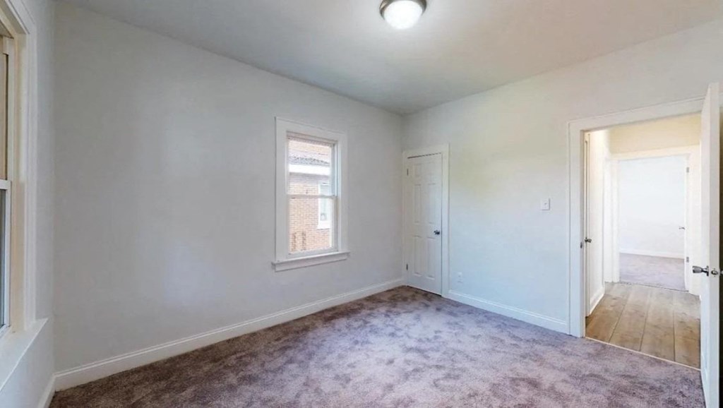 an empty living room with a door and a window