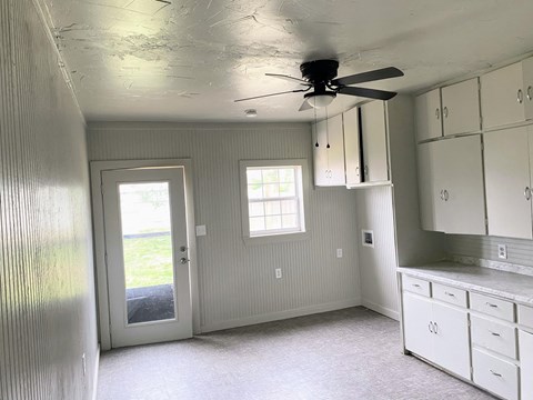 a kitchen with white cabinets and a ceiling fan