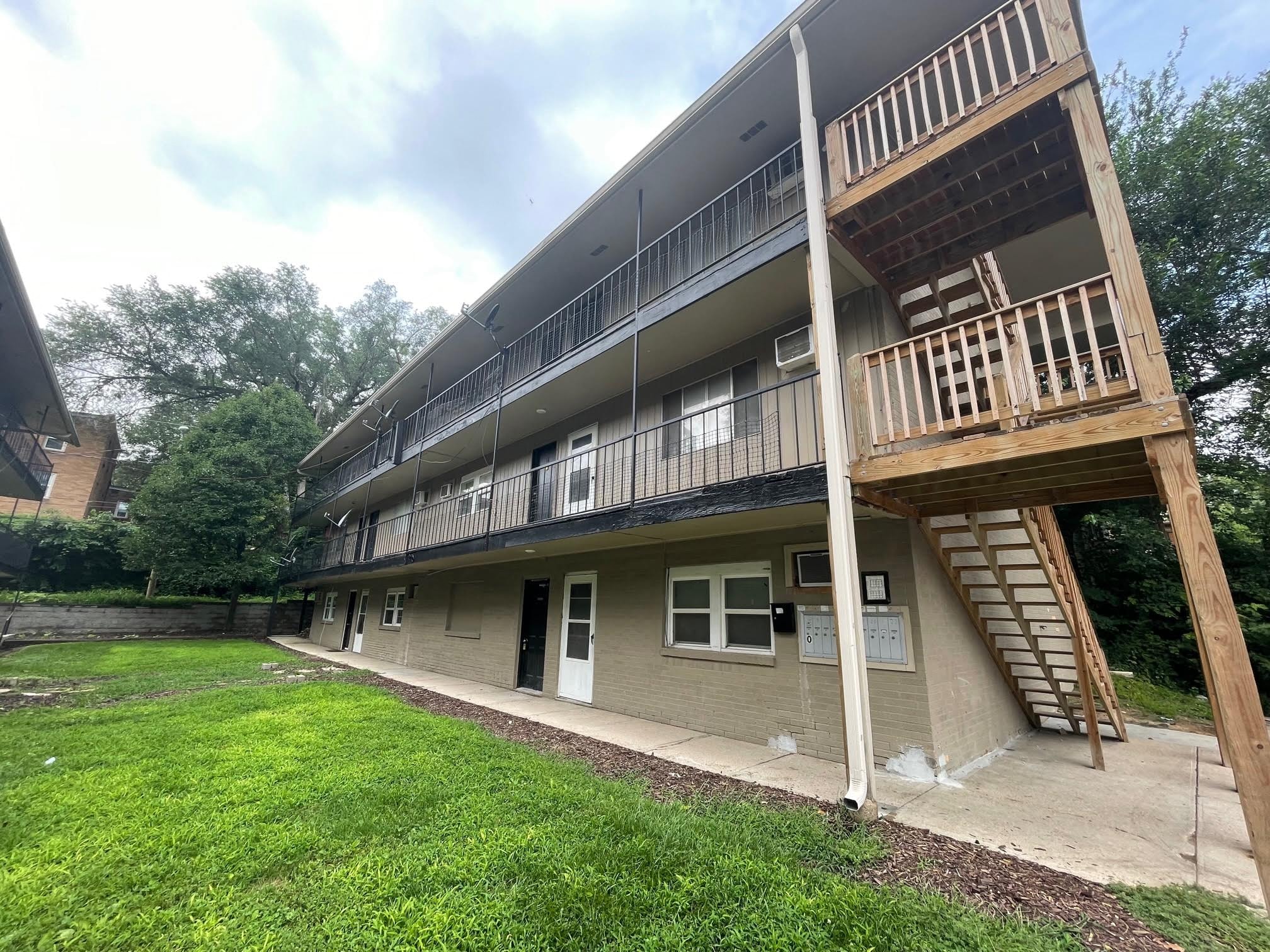the back of a building with a yard and a balcony