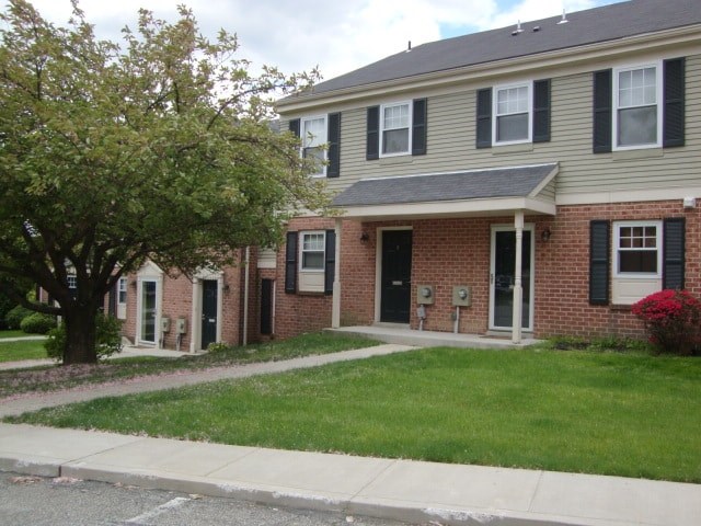 A house with a green lawn and a tree in front.