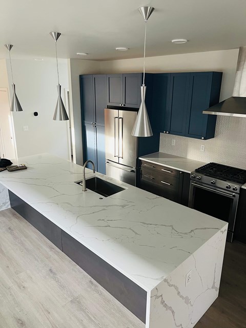 A kitchen with a marble counter top and blue cabinets.