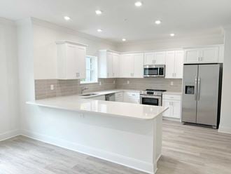 a white kitchen with a large island and stainless steel appliances