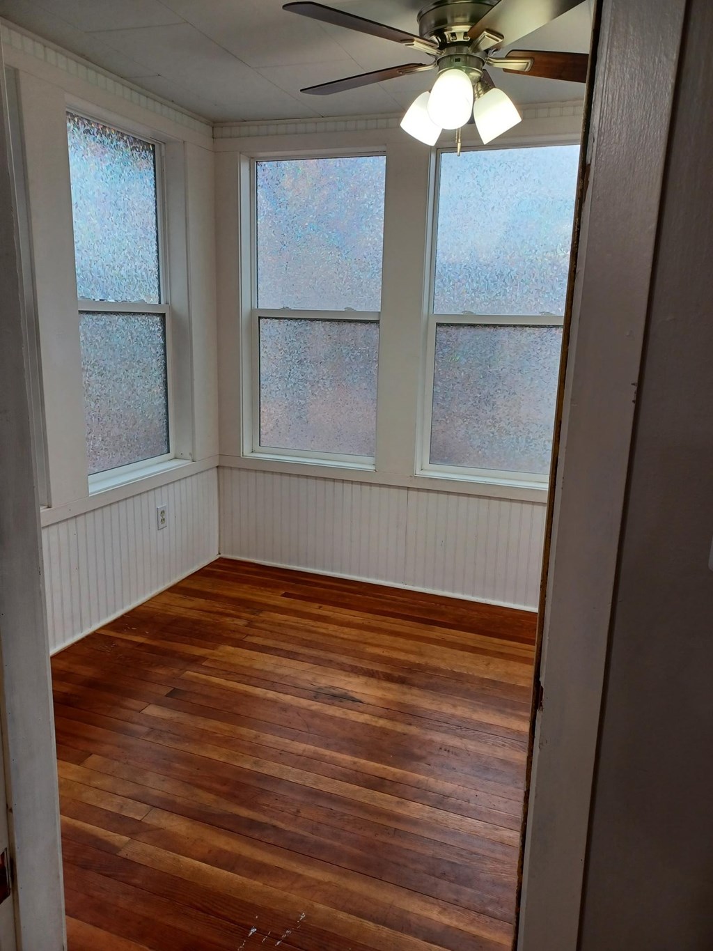 A room with a ceiling fan and wooden flooring.