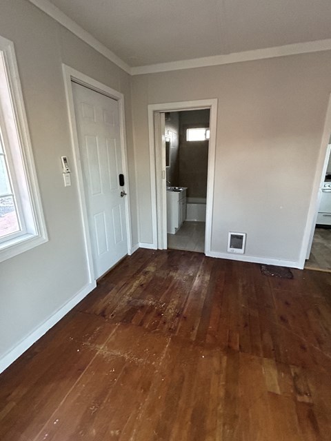 a living room with wooden floors and a door to a bathroom