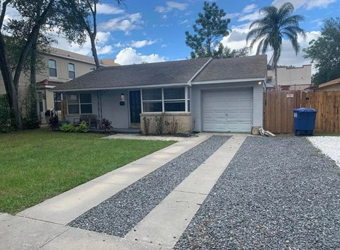 a house with a gravel driveway and a blue trash can