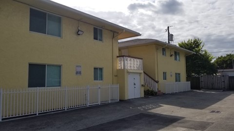 A yellow building with a white fence in front.