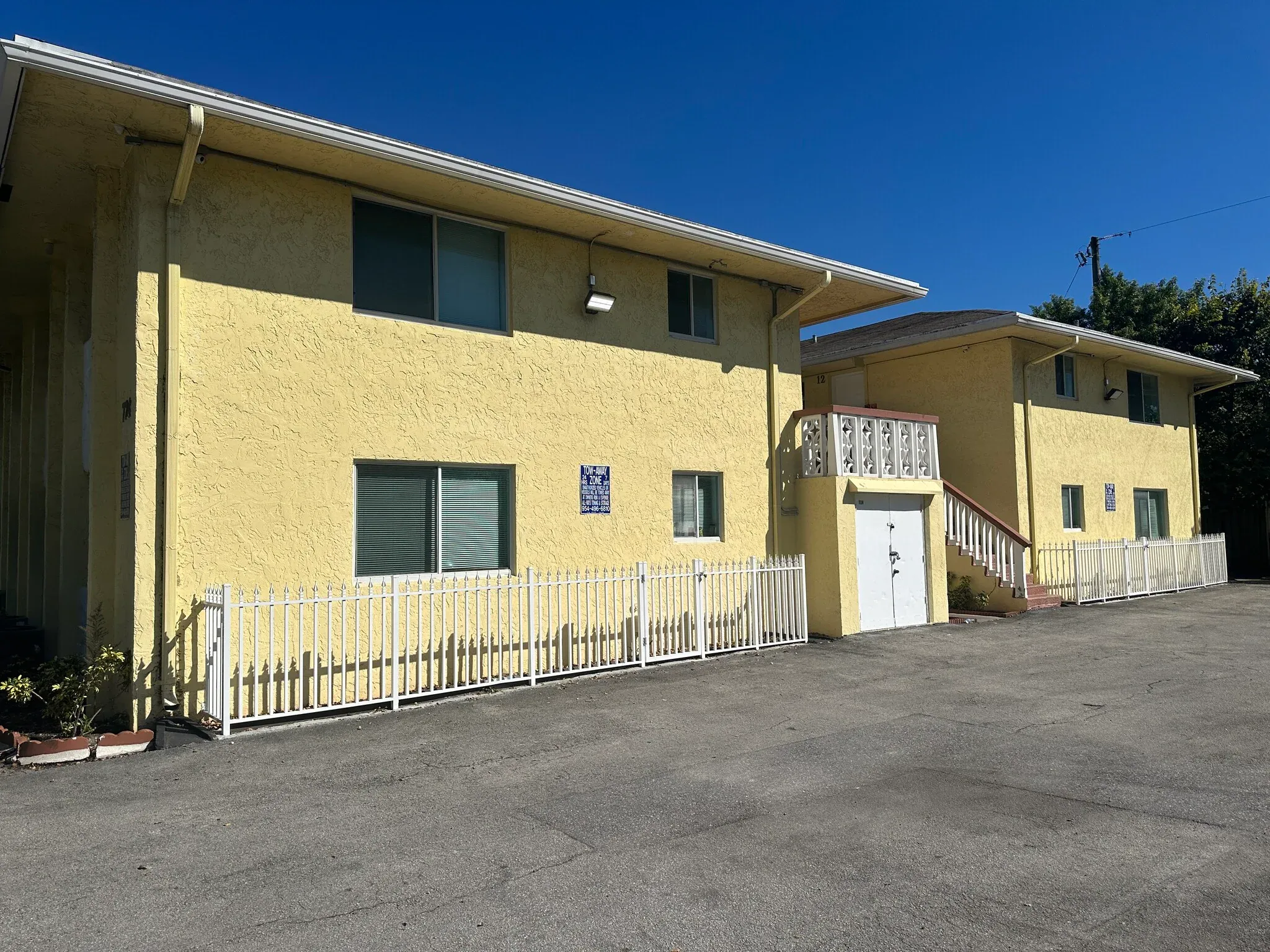 A yellow building with a white fence in front.
