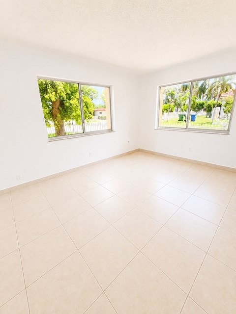 Empty room with two windows and tiled floor.