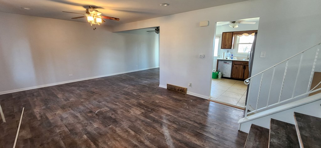 an empty living room with a hard wood floor and a ceiling fan
