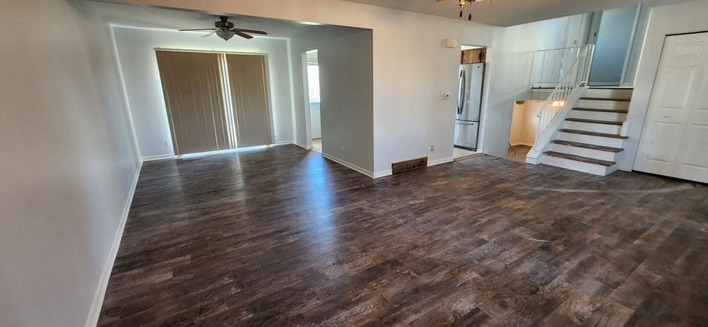 an empty living room with wood floors and a staircase