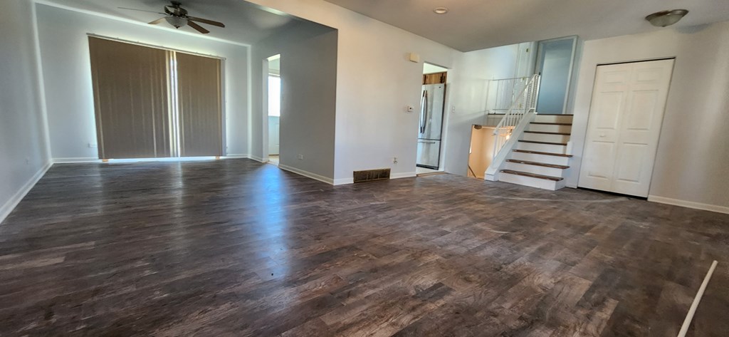 an empty living room with wood floors and a staircase