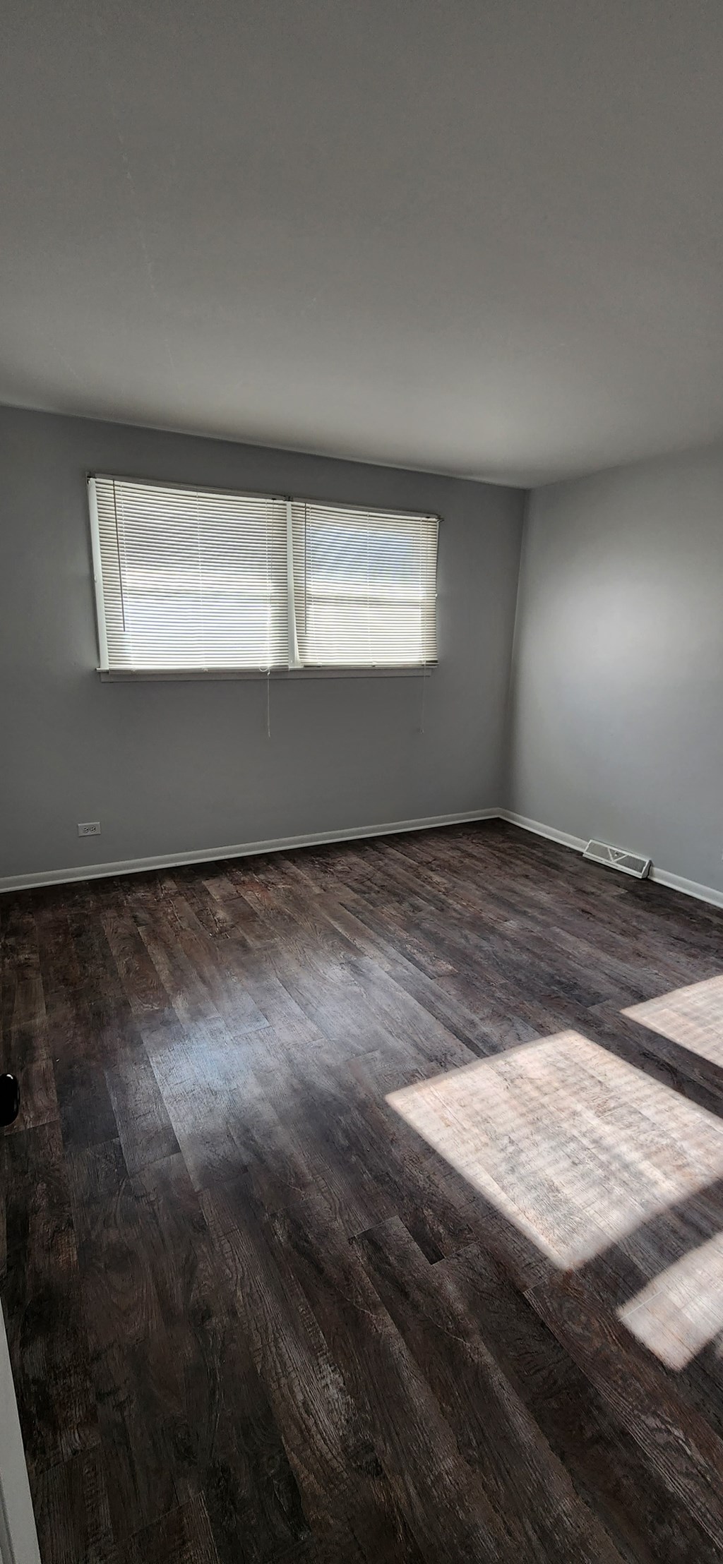 an empty room with wooden floors and two windows