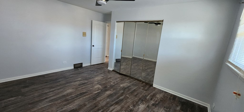 a bedroom with white walls and a mirrored closet