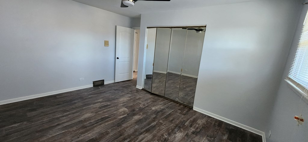 a bedroom with white walls and a mirrored closet