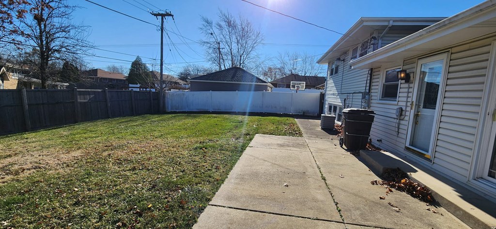 a backyard with a fence and a sidewalk and a house
