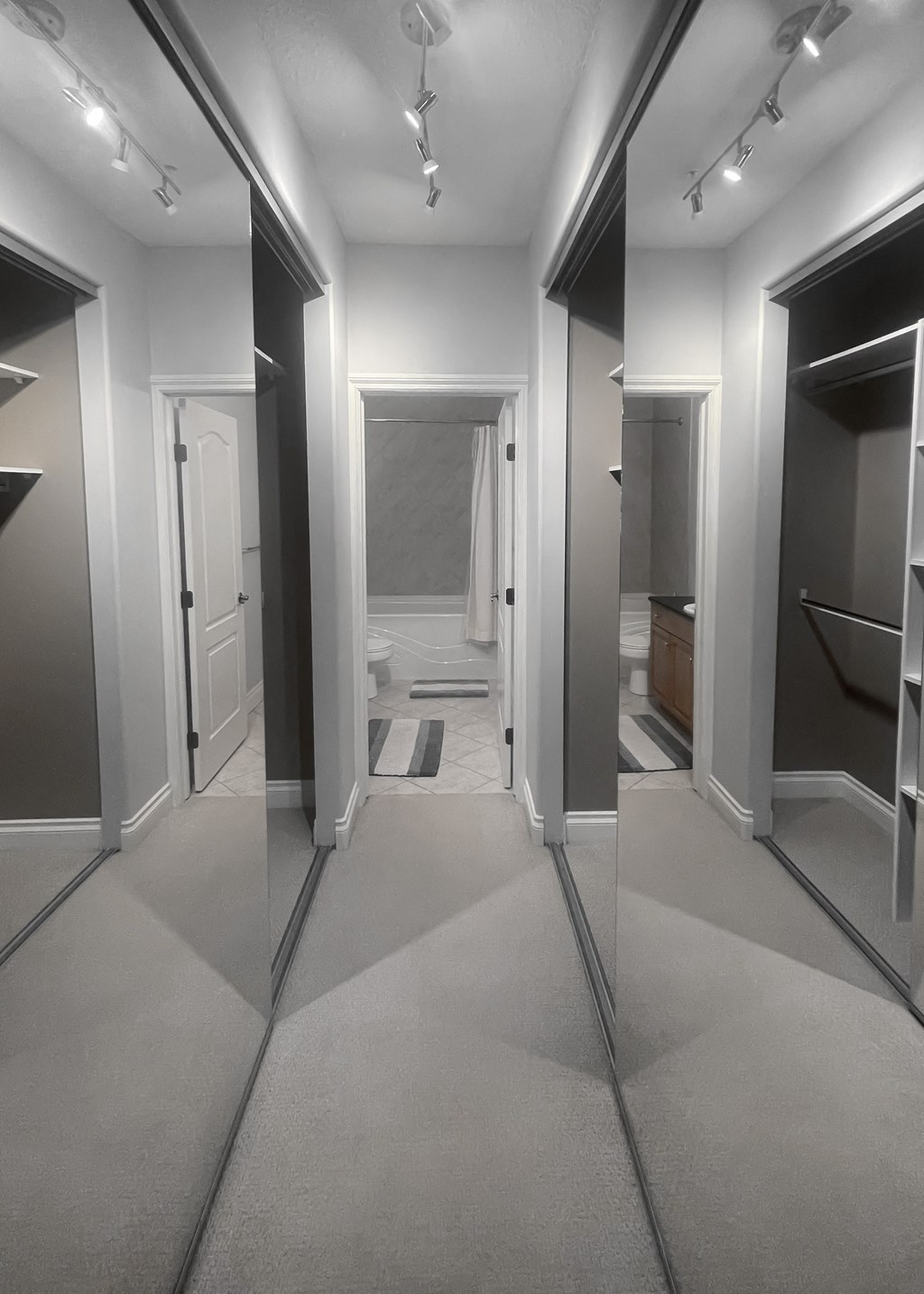 a row of mirrors in a hallway with a bathroom in the background