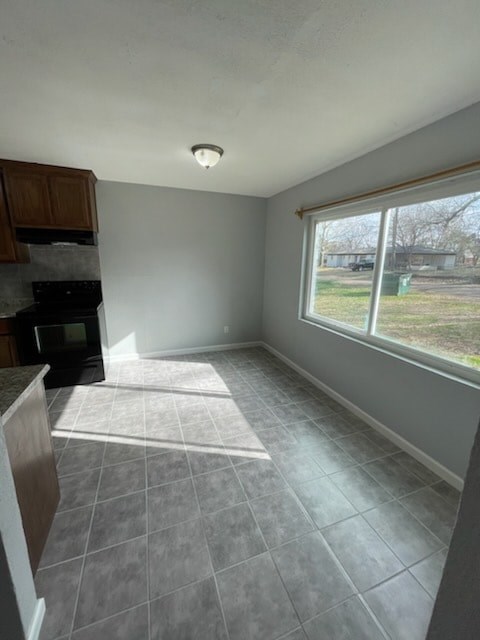 A kitchen with a black stove and a window overlooking a yard.