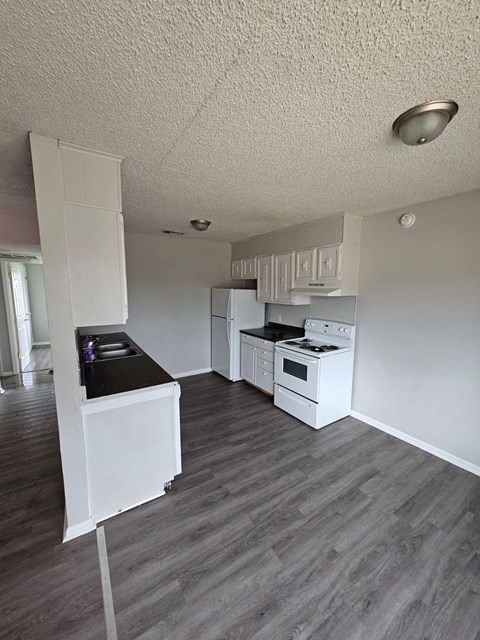 A kitchen with white appliances and a black countertop.