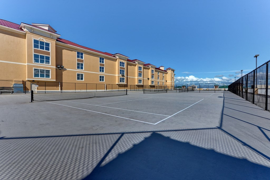 an empty tennis court in front of a building