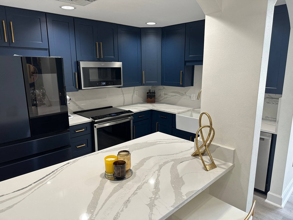 a kitchen with navy blue cabinets and white counter tops