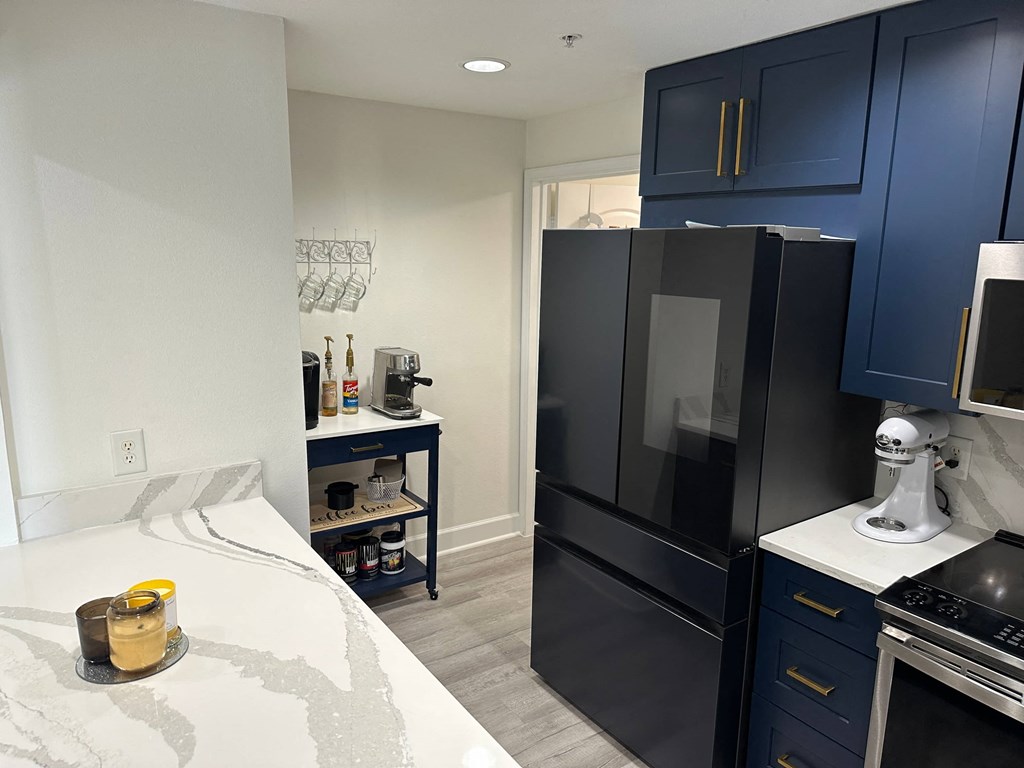 a black refrigerator freezer sitting in a kitchen next to a bed