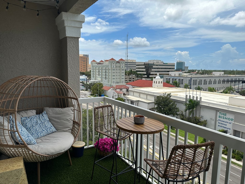 a balcony with a chair and a table and a city in the background