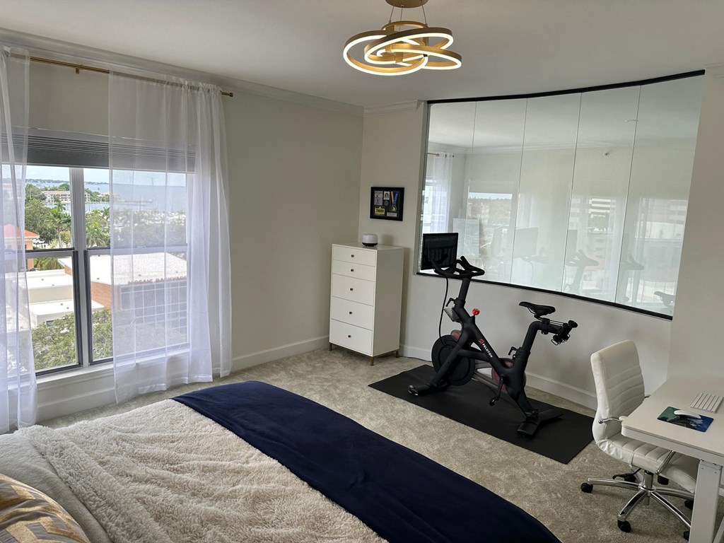 a bedroom with a bed and a desk with an exercise bike