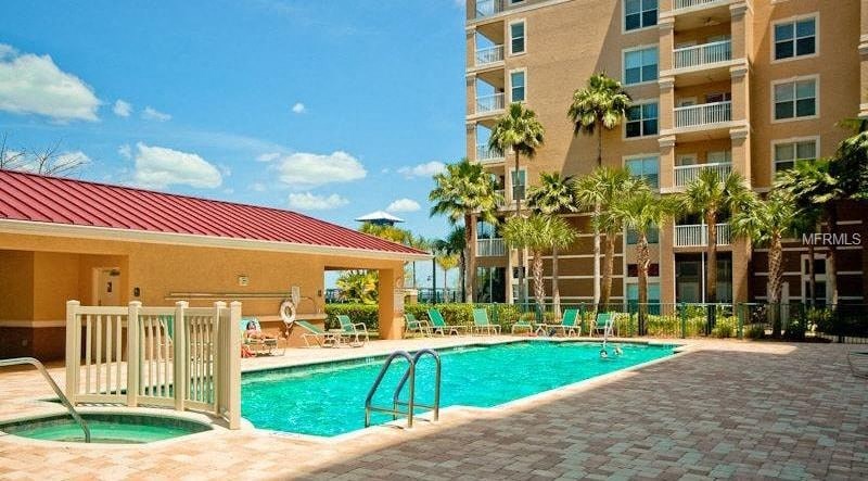 a swimming pool next to an apartment building with palm trees