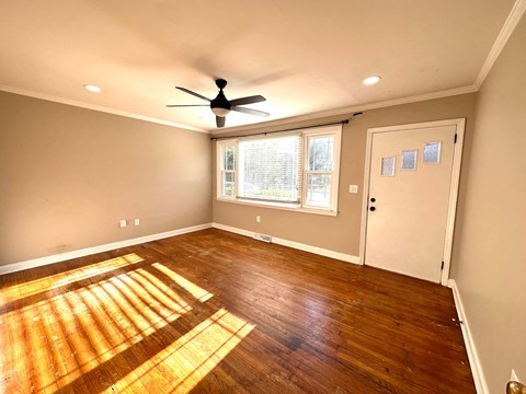 an empty living room with wooden floors and a ceiling fan
