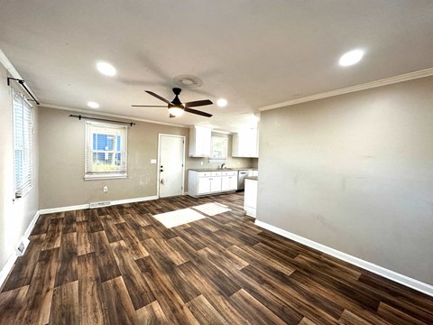 an empty living room with a ceiling fan and a kitchen