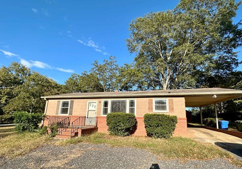 a small brick house with a front porch and a tree