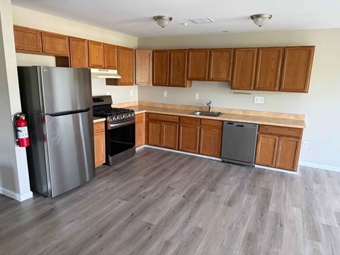 A kitchen with wooden cabinets and a grey fridge.