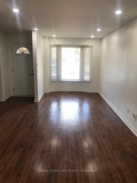 an empty living room with wooden floors and a window