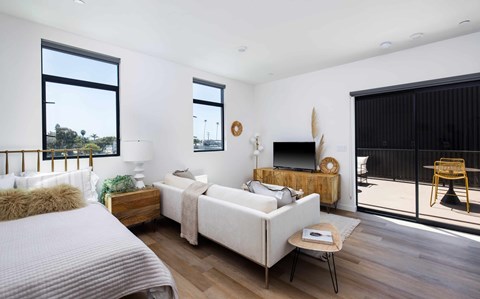 A bedroom with a bed, a couch, a chair, and a television.