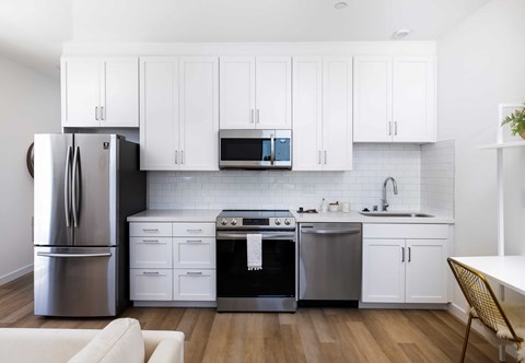 A modern kitchen with white cabinets and stainless steel appliances.