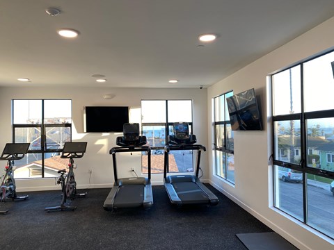 A gym with treadmills, exercise bikes, and a television.