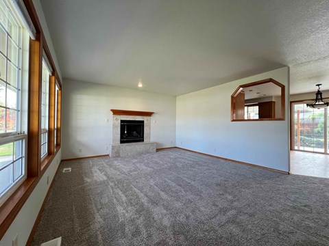 A spacious living room with a fireplace and large windows.