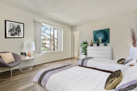 A bedroom with a large bed and a chair.