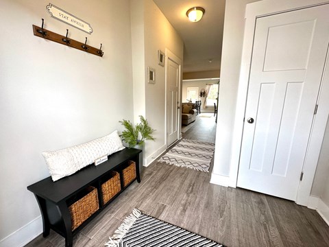 a hallway with white walls and a white door and a black and white rug