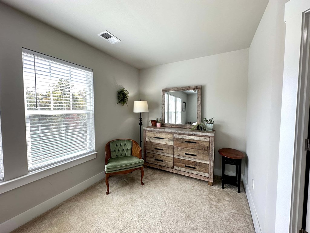 a living room with a chair and a dresser and a window