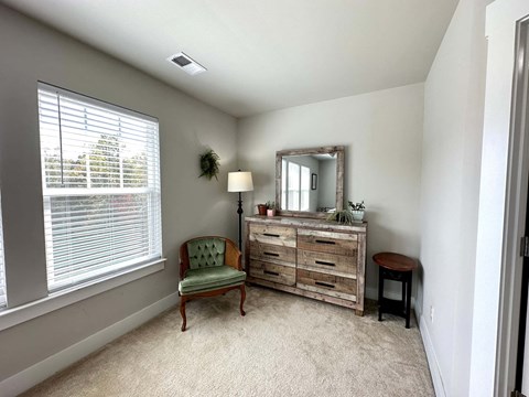a living room with a chair and a dresser and a window
