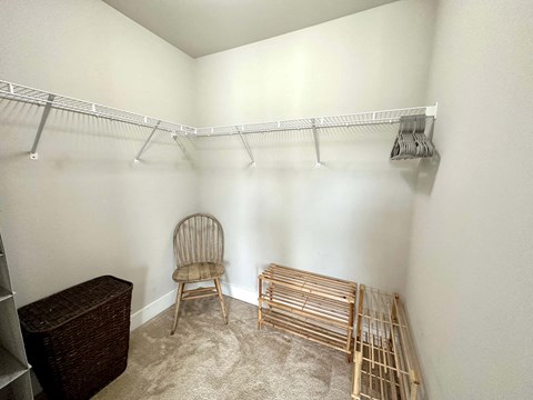 a walk in closet with a chair and a rack on the wall