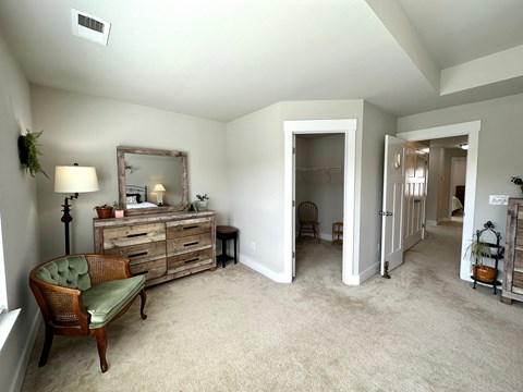 a living room with a couch and a chair and a hallway with a dresser